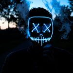 Een vrouw gebruikt een LED gezichtsmasker voor roodlichttherapie thuis voor anti-aging.
