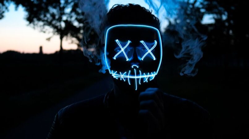 Een vrouw gebruikt een LED gezichtsmasker voor roodlichttherapie thuis voor anti-aging.