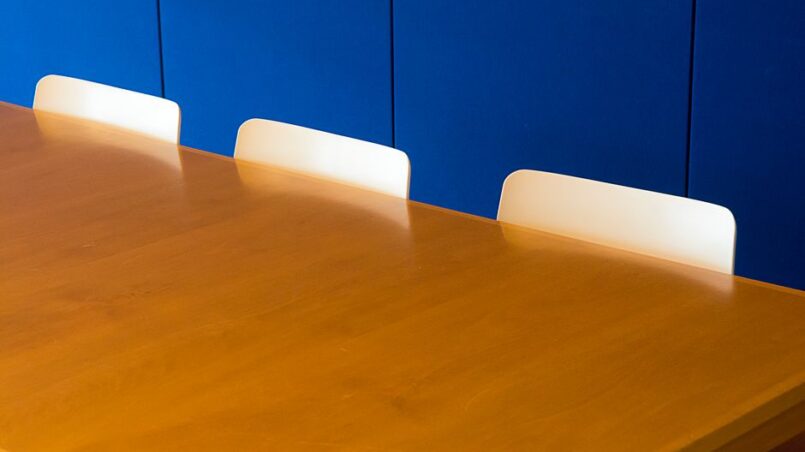 Een stijlvolle vergadertafel van verschillende houtsoorten in een moderne vergaderruimte.